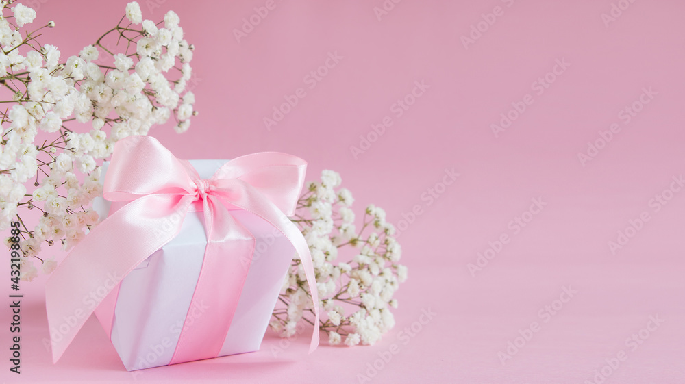 Gift box and a bouquet of blooming gypsophila on a pink background. Mother's day holiday concept. Copy space. Gift box and a bouquet of blooming gypsophila on a pink background. Mother's day holiday concept. Copy space.