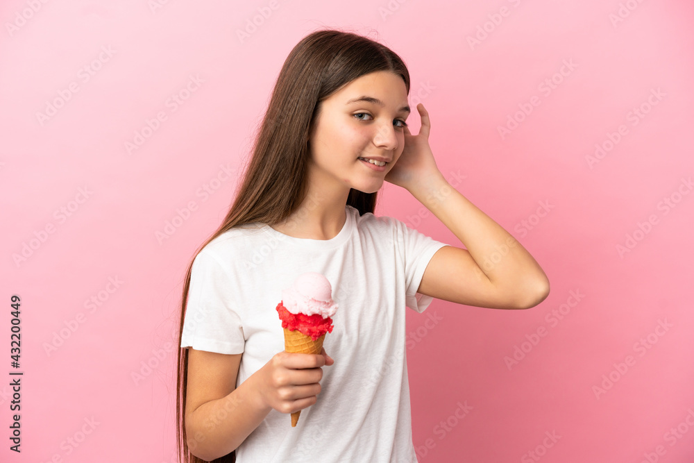 Little girl with a cornet ice cream over isolated pink background listening to something by putting hand on the ear Little girl with a cornet ice cream over isolated pink background listening to something by putting hand on the ear