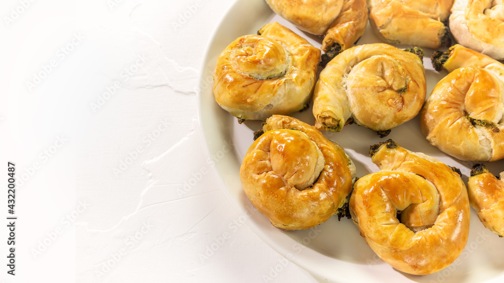 Mediterranean cuisine. Food banner with a national Greek causing with homemade pies with feta cheese and spinach on a white background with copy space. Healthy home baking pastries Mediterranean cuisine. Food banner with a national Greek causing with homemade pies with feta cheese and spinach on a white background with copy space. Healthy home baking pastries