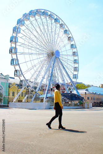 Ferris wheel against the blue sky. Girl Looks Ferris Wheel Rear View Modern Ferris Wheel	
