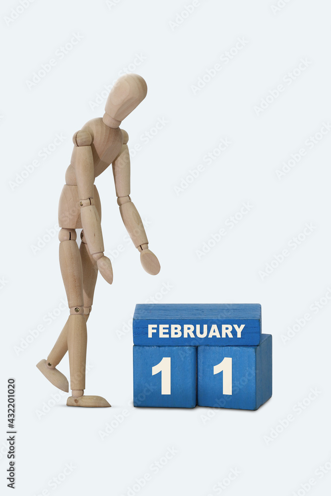 day of the month 11 February calendar . A calendar date on blue cubes and a wooden man standing next to it. White background day of the month 11 February calendar . A calendar date on blue cubes and a wooden man standing next to it. White background