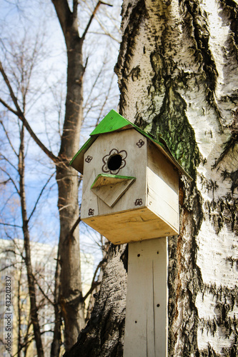 Birdhouse on a tree. Wooden bird house on a tree trunk in a green park outdoors.