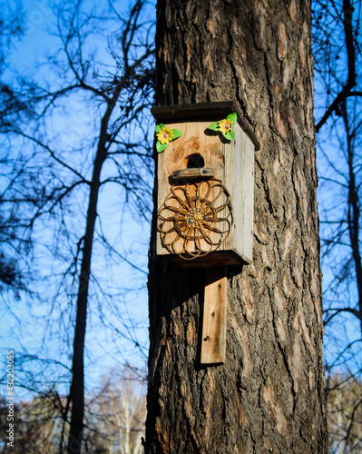 Birdhouse on a tree. Wooden bird house on a tree trunk in a green park outdoors.