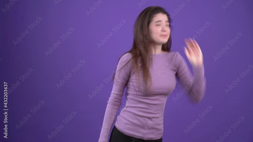 Panicked young woman, shouting loudly around for help. She is wearing a purple sweater in the studio on a purple background Panicked young woman, shouting loudly around for help. She is wearing a purple sweater in the studio on a purple background