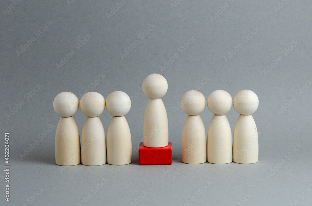 Team and leader on a gray background. Wooden figures in the image of people. Chief at work, leadership and personnel management, business concept. Team and leader on a gray background. Wooden figures in the image of people. Chief at work, leadership and personnel management, business concept.