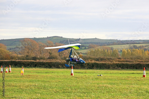 Canvas-taulu Ultralight airplane landing on a grass strip