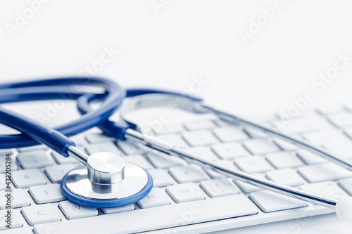 Close up of a Stethoscope on computer keyboard on white desk. Online health care or telemedicine concept. Medical background