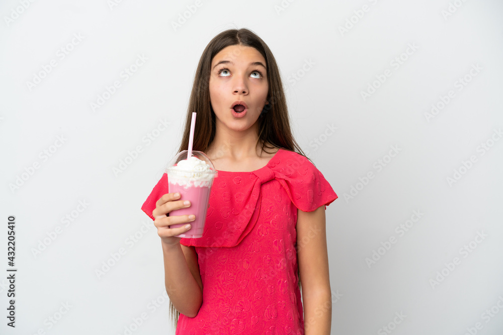 Little girl with strawberry milkshake over isolated white background looking up and with surprised expression Little girl with strawberry milkshake over isolated white background looking up and with surprised expression