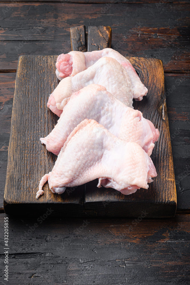 Chicken wings, on wooden cutting board, on old dark  wooden table background