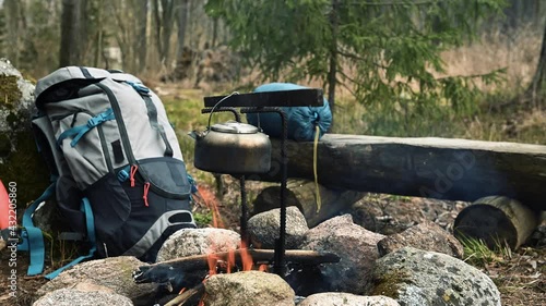Backpack and Metal kettle on a campfire in the forest