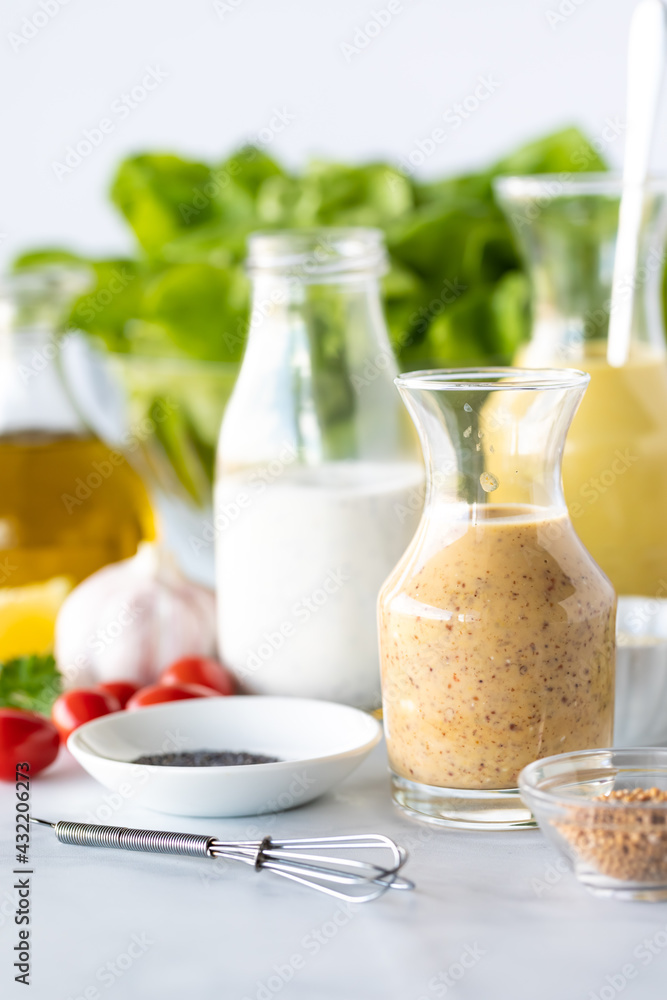 Straight on view of glass bottles with homemade salad dressing and honey mustard in front.