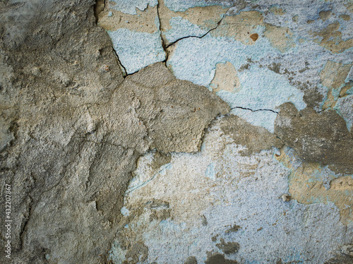 Weathered and cracked concrete wall maintained through time with blue lime and different mortar mixes. Peeling plaster from cement structure surface. Construction element, abstract texture background