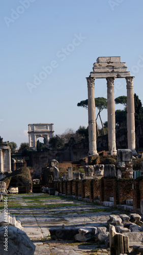 Rome, Italy, January 2007: Detail of the Roman Forum on the Via Sacra, with the three column of Castor and Pollux temple ruins and the Tito`s Arch on the background.