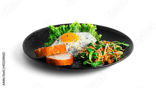 Fried egg with vegetable salad and bread in black plate isolated on a white background.