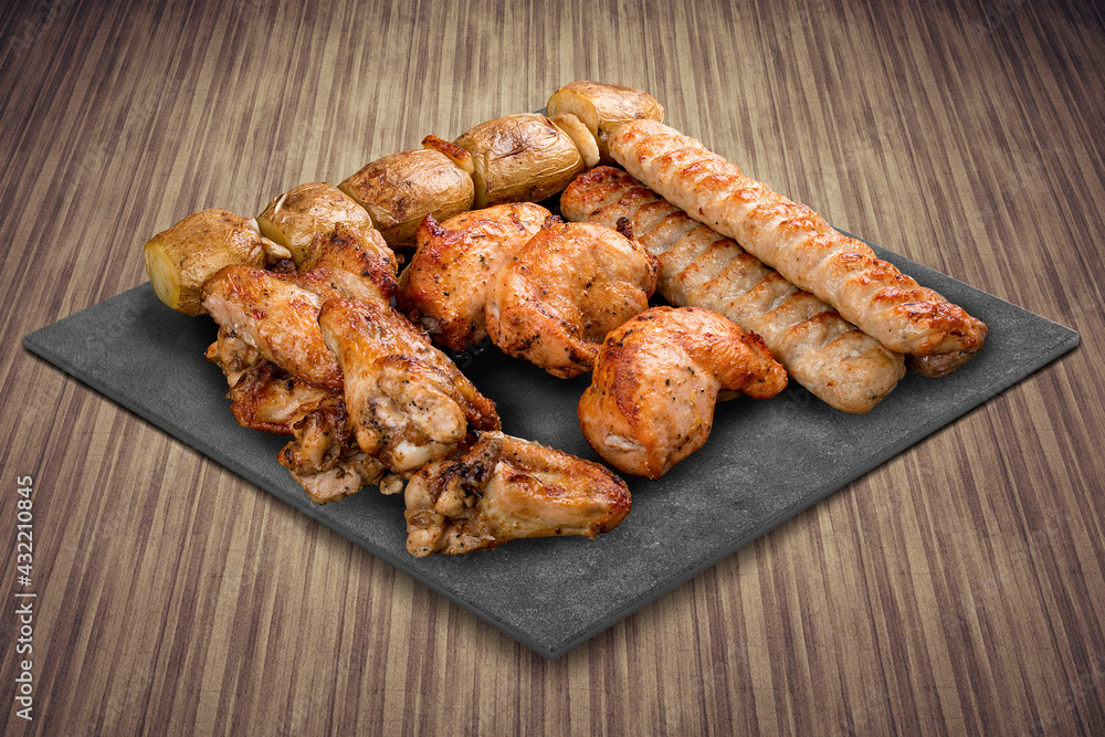 A selection of various barbecued gourmet meats on a black board with a rustic timber background. Assorted meat A selection of various barbecued gourmet meats on a black board with a rustic timber background. Assorted meat