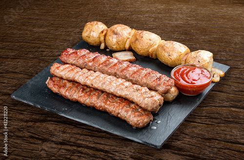 Stone board with different tasty cooked meat on wood background. Various kebab with baked potatoes