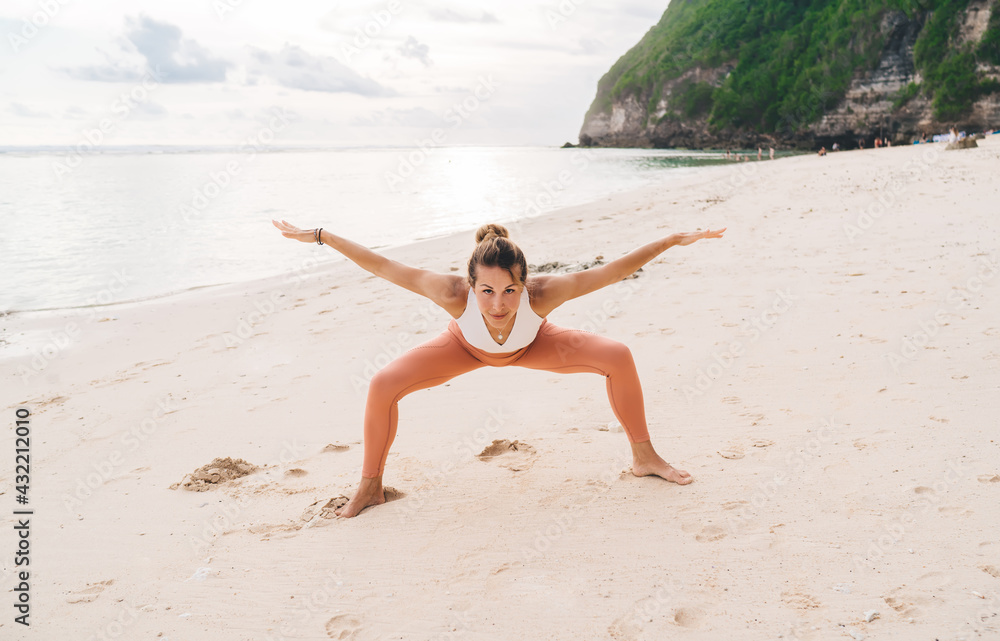 Fit woman practicing yoga near ocean