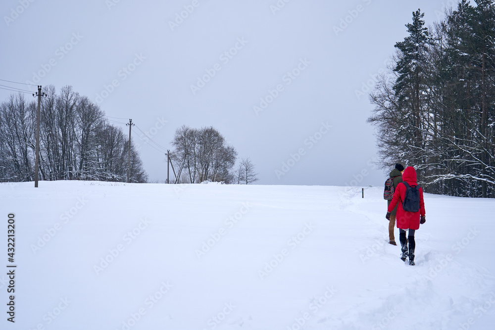 People walking in the snow in the field near the forest. People walking in the snow in the field near the forest.