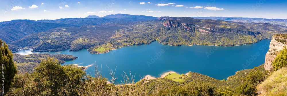 Great aerial panorama of the Sau reservoir overlooking a large part of the reservoir, with the Munts cliffs and the Montseny mountain. Tavertet. Collsacabra, Osona, Catalonia, Spain