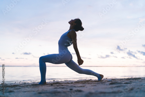 Young lady practicing asana of yoga against sea
