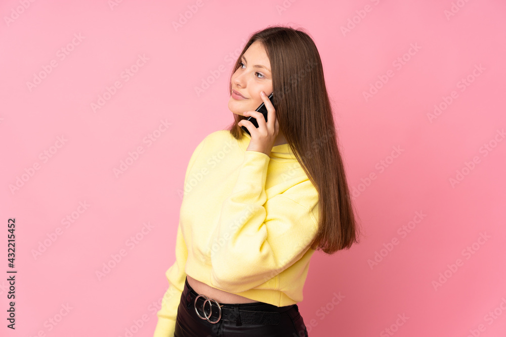 Fototapeta premium Teenager caucasian girl isolated on pink background keeping a conversation with the mobile phone with someone