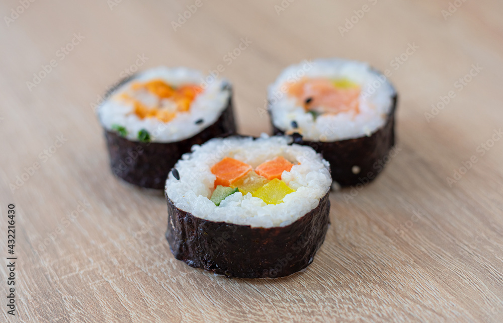 Three rolls of sushi on a wooden background Three rolls of sushi on a wooden background