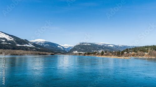 wide Columbia river with snow in mountains blue sky early spring British Columbia Canada