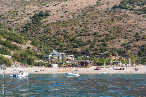 View of the strip of the sea with yachts, beach and mountains surrounded by vegetation, Albania. Travel and vacation theme