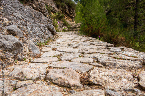 Cobblestone path going through large rocks in a ravine. In the famous Barranc del Cinc de Alcoy, Alicante (Spain) photo