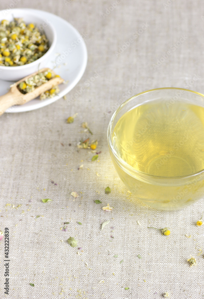 Chamomile herbal tea in glass cup and jar with dry herb flowers, above overhead view, naturopathy, natural medicine, healing drinks for sleep, skin and hair care concept Chamomile herbal tea in glass cup and jar with dry herb flowers, above overhead view, naturopathy, natural medicine, healing drinks for sleep, skin and hair care concept
