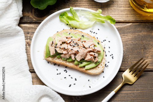 Avocado, canned tuna and boiled egg toast on wooden table background. Healthy food, avocado open sandwich for breakfast or lunch. Flat lay, top view, close up