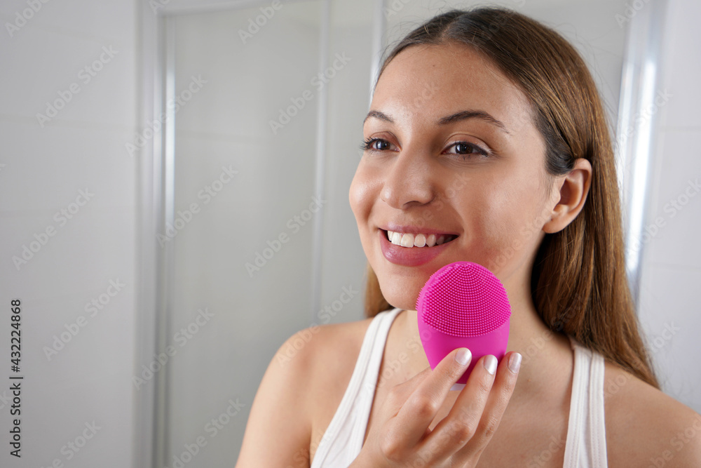 Close up of smiling girl cleaning skin with silicon brush ultrasonic in the bathroom Close up of smiling girl cleaning skin with silicon brush ultrasonic in the bathroom