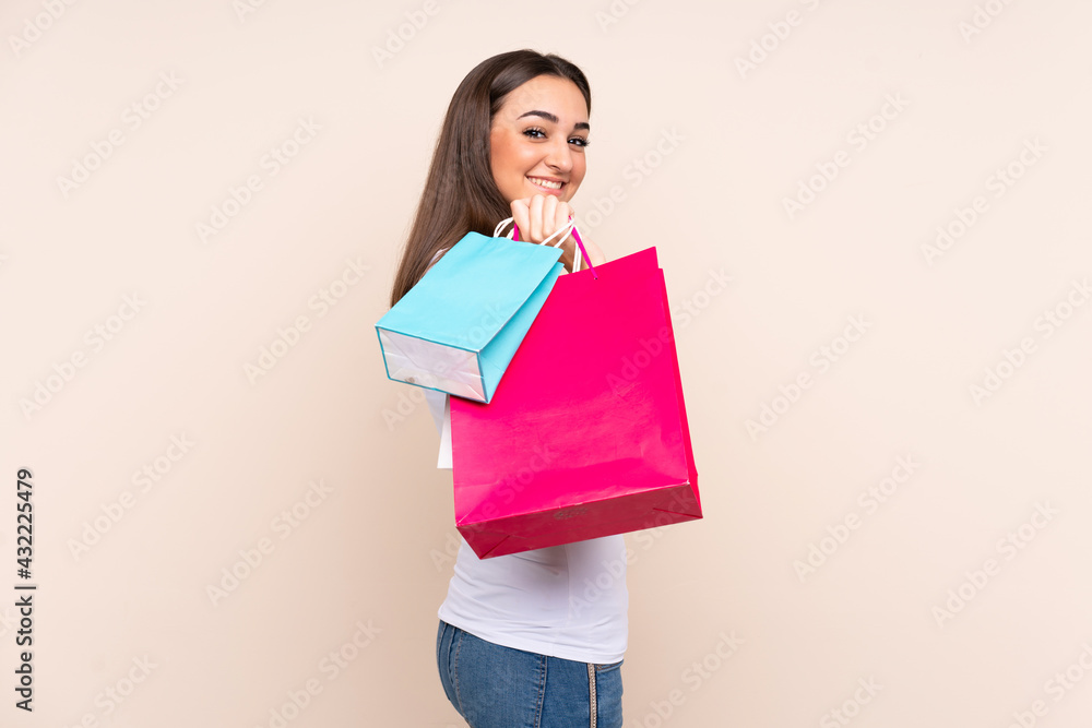 Young caucasian woman isolated on beige background holding shopping bags and smiling Young caucasian woman isolated on beige background holding shopping bags and smiling
