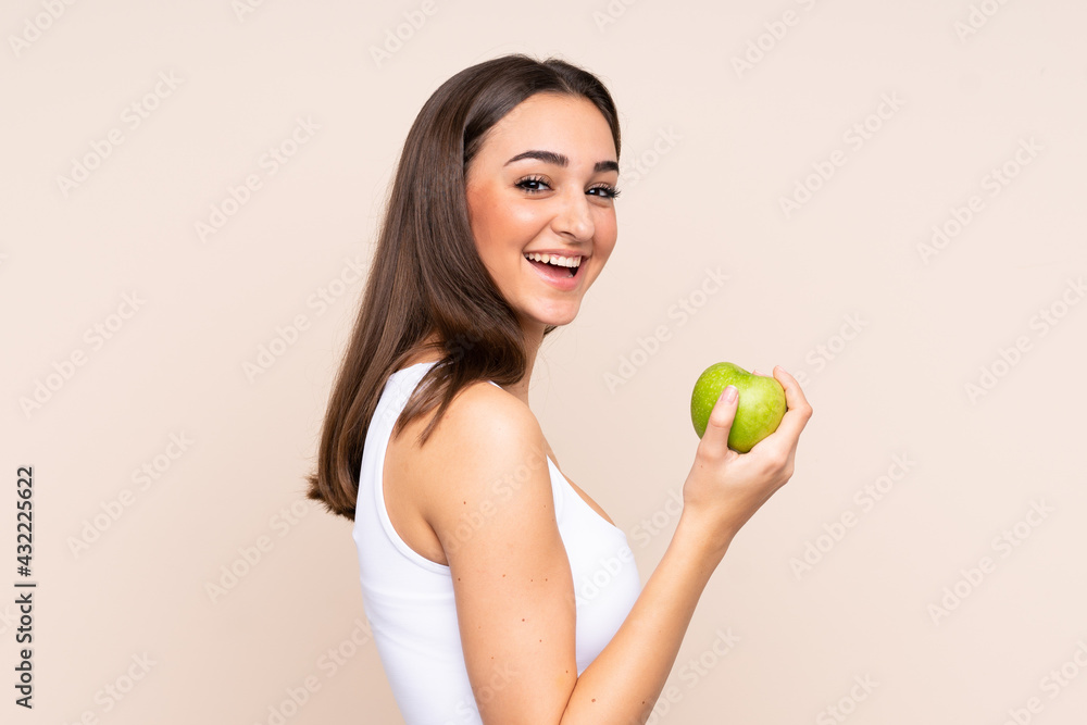 Young caucasian woman isolated on beige background with an apple and with a bottle of water Young caucasian woman isolated on beige background with an apple and with a bottle of water