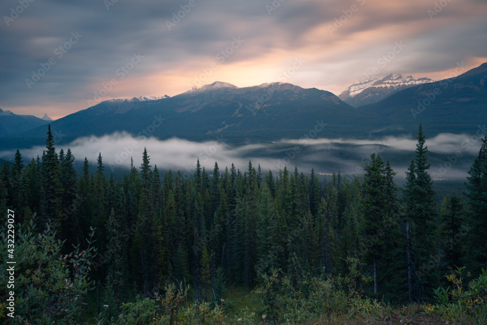 Long exposure of mist rolling through the valley in Banff National Park in the early morning. Blue hour with sparse sunlight in Canadian Rockies. Morning in the mountains of Alberta, CAN.
