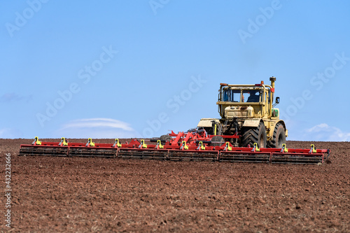 Seasonal agricultural work in the field. Heavy tractor with harrow close-up. Copy space.