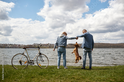 young couple walks by the lake with a dog