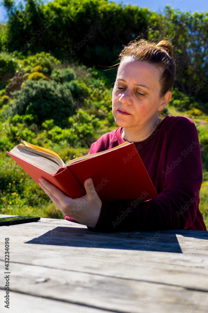 Mujer joven senatada en el parque leyendo un libro Mujer joven senatada en el parque leyendo un libro