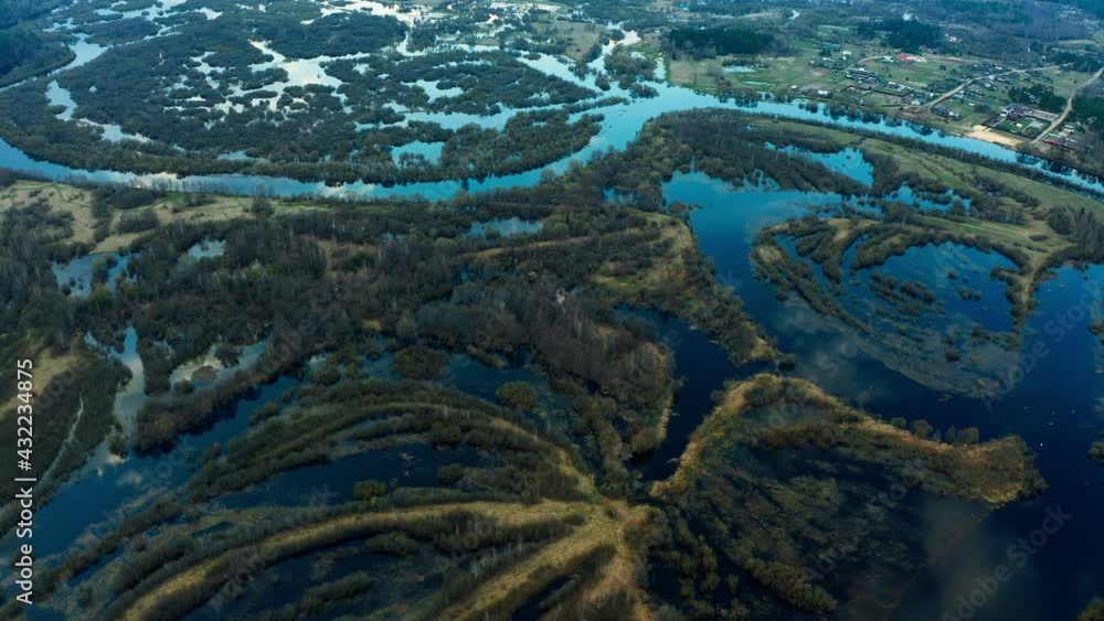 Spring flood, overflow of a large river from a bird's eye view. Full-flowing river Berezina, Belarus. Flooded fields and bushes. High water on the river, river bends. Spring flood, overflow of a large river from a bird's eye view. Full-flowing river Berezina, Belarus. Flooded fields and bushes. High water on the river, river bends.