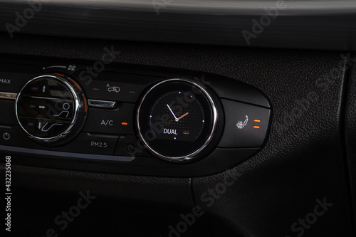 Сlose up view of digital car clock inside modern black car interior. Car dashboard with temperature, blower and air conditioner controllers.