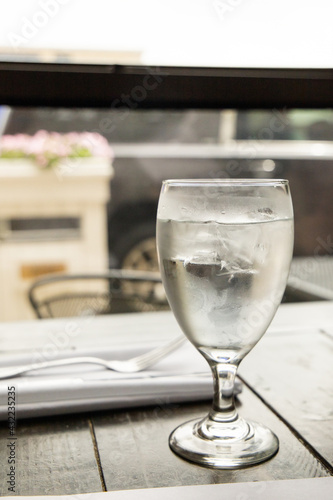 A water glass and a silverware setting on a wood table at a high end restaurant