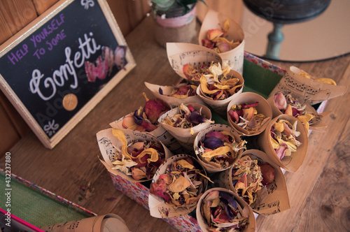 Rose petal dried confetti on cones close up with blackboard sign at a wedding 