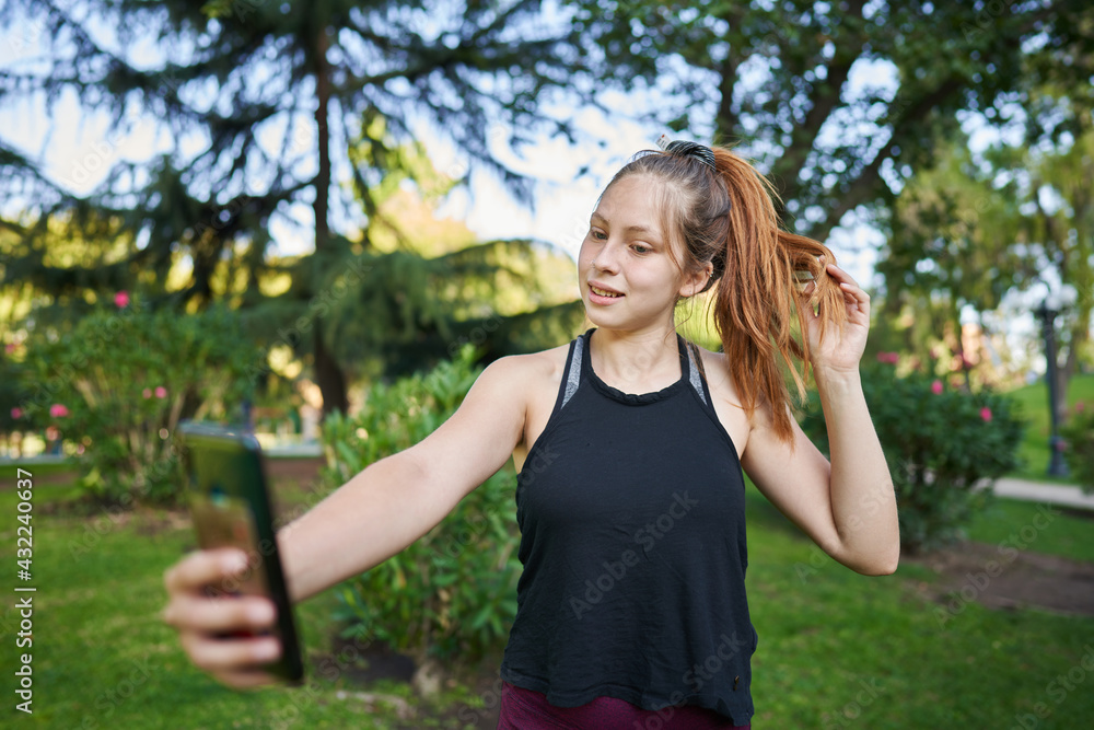 a beautiful green-eyed red-haired girl in a medium shot smiles while taking a selfie with her phone and listening to music a beautiful green-eyed red-haired girl in a medium shot smiles while taking a selfie with her phone and listening to music
