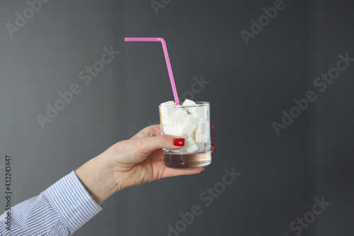 Female hand holds glass with sugar cubes and straw photo