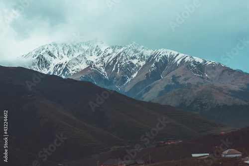 Snow-capped peaks and dark rocks. Dramatic landscape. Winter mountains, alpine skiing. Sunny snowy hills. Panoramic mountain view. Rocks and white slopes covered with glaciers