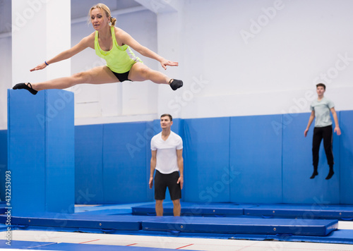 Portrait of focused sports girl during training in trampoline center. Skills and drills of side split..