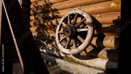 An antique wooden wheel from a carriage or carriage hangs on a log wall. Rustic vintage concept