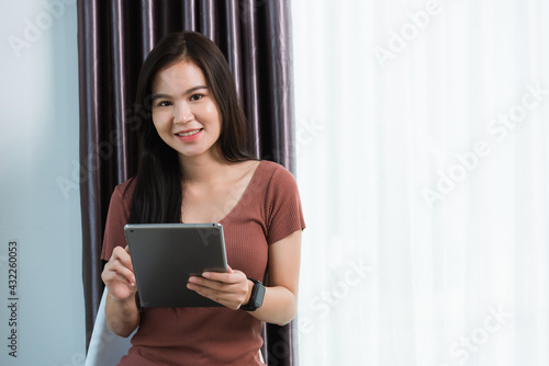 Work from home, Happy Asian young businesswoman smile video conference call or facetime by modern digital smart tablet computer she uses finger touching on screen, looking to camera at the home office