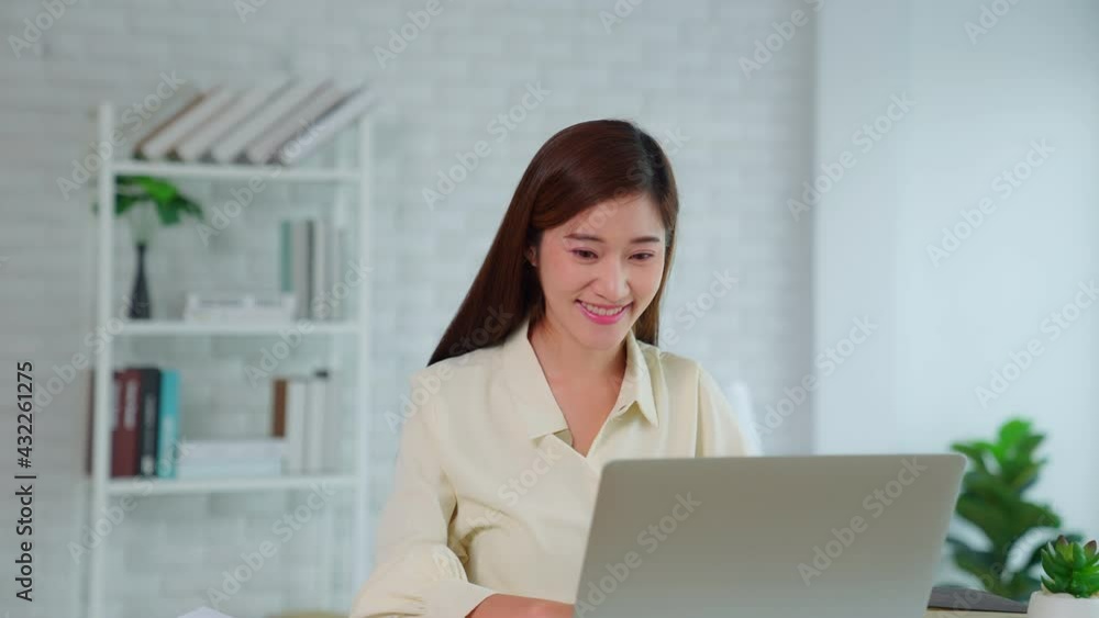 A beautiful Asian woman working on a laptop. A girl printed her work and smiled happily and turned her head to look at the window with positive emotions . A beautiful Asian woman working on a laptop. A girl printed her work and smiled happily and turned her head to look at the window with positive emotions .