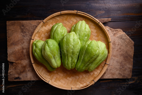 Chayote squash fruit (Mirliton, pipinola or choko) in a basket on wooden background, Edible fruit eaten both cooked and raw such as salad or salsa photo